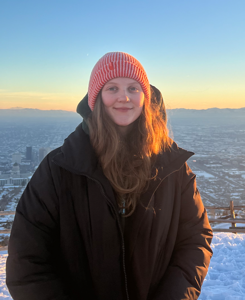 Victorya Richardson standing outdoors in the snow overlooking Salt Lake City